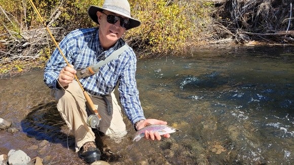 Dave Dozer with a fish in a shallow stream