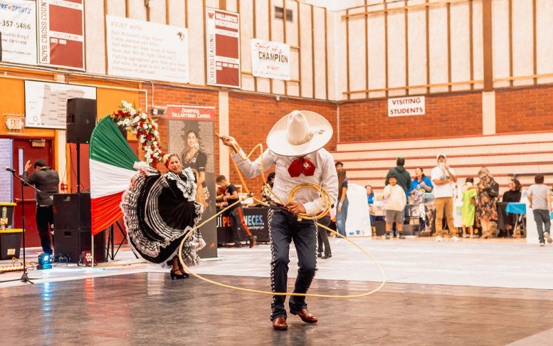 Antonio swings a rope while a woman dances in the background at an assembly.