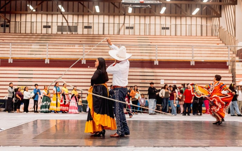 Antonio swings a rope circle around himself and a woman at an assembly.. 