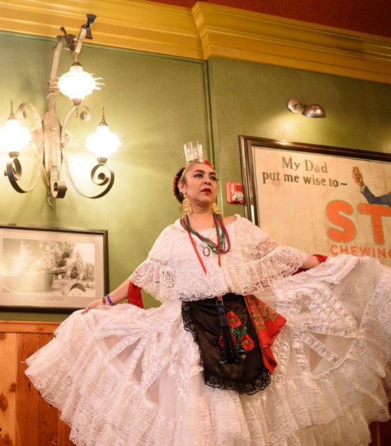 Kenya Marquez demonstrates traditional mexican folk dancing, wearing a long white skirt and balancing a candle on her head.
