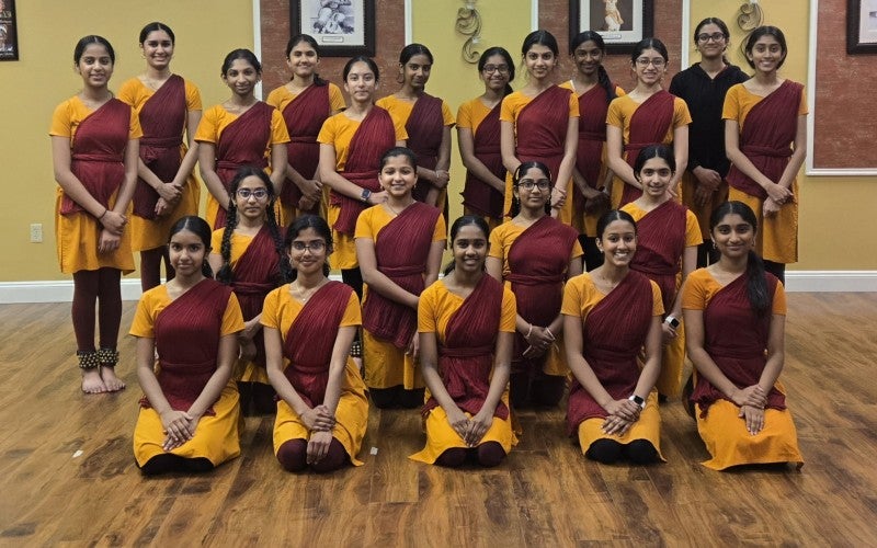 A group of dancers in red and yellow salwar kameez