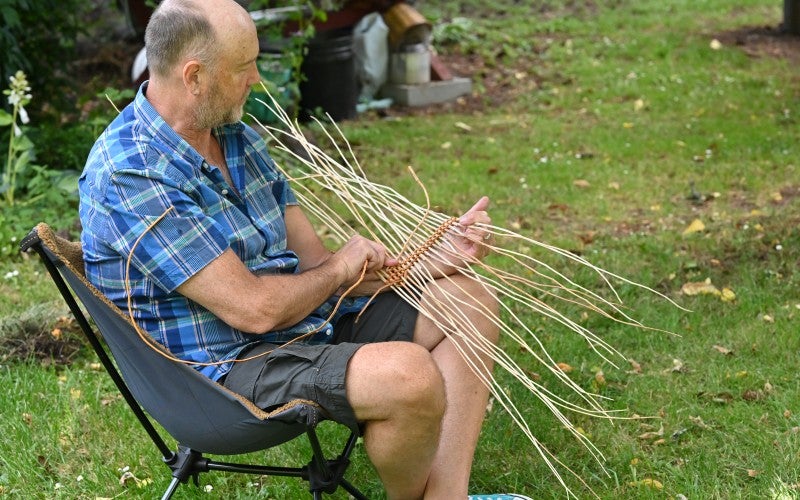 Andrew sitting and weaving, 2022.