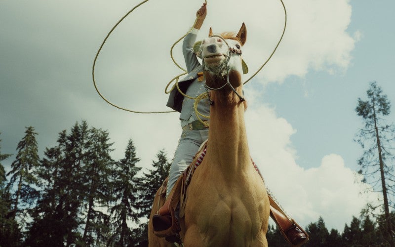 Antonio swings a rope around his head while on horseback.
