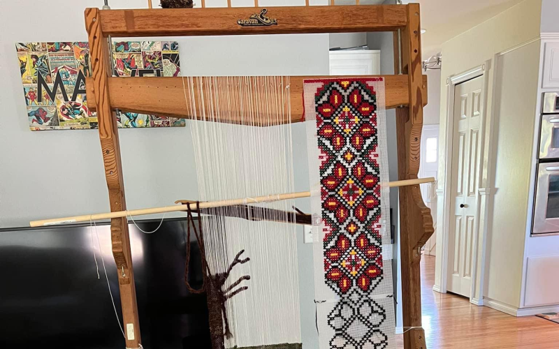 A loom, with a colorful weaving in progress.