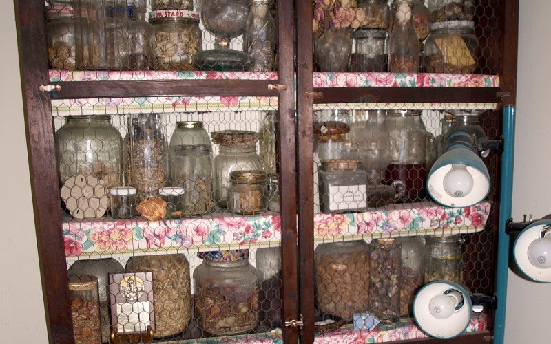A wooden cabinet full of jars.