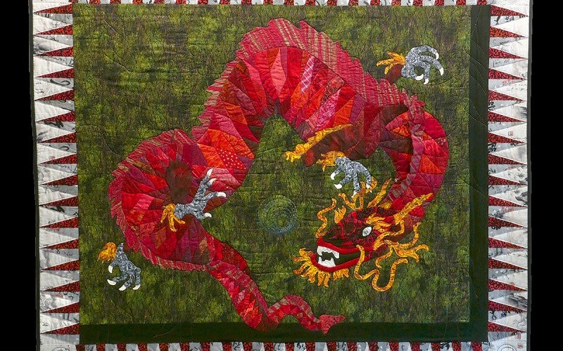 A quilt with a red dragon on a green background