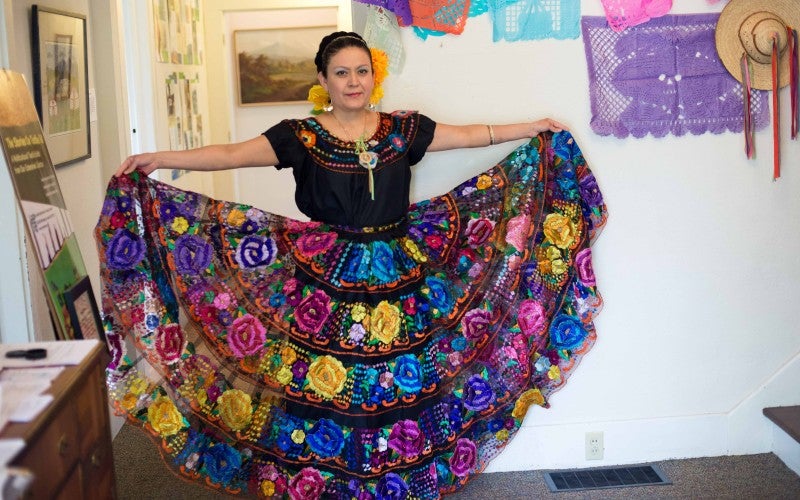 Maria Laguna poses while wearing a colorful traditional ballet folklorico dress.