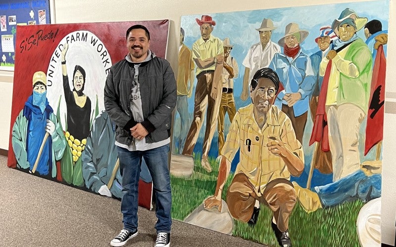 Melendrez poses in front of his artwork.