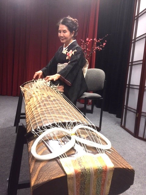 the artist Masumi sits playing her koto, fully engrossed in her playing