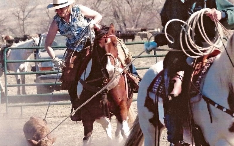 Dan and Robin Fulwyler ride dark brown horses and rope a brown calf.