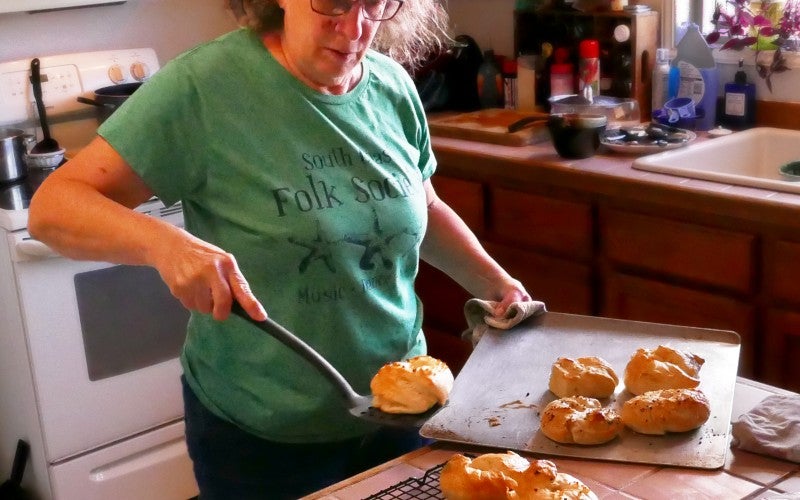 Stacy Rose placing freshly baked bread on a wire rack to cool