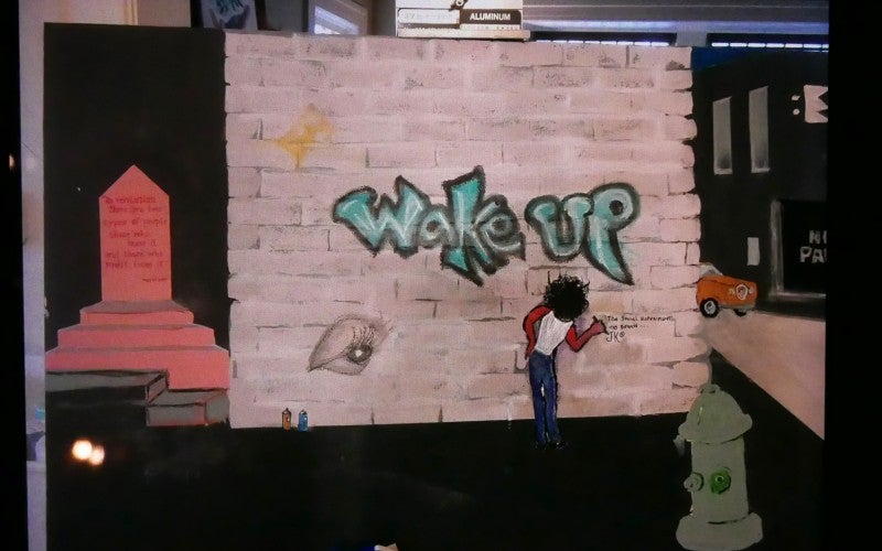 Painting by Jardin Kazaar. The painting contains the words "wake up" graffitied on a walk
