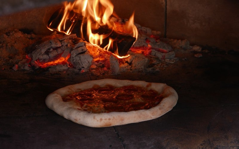 A pizza cooking inside a wood oven