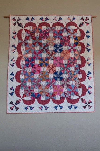 A patterned quilt hanging up on a wall.