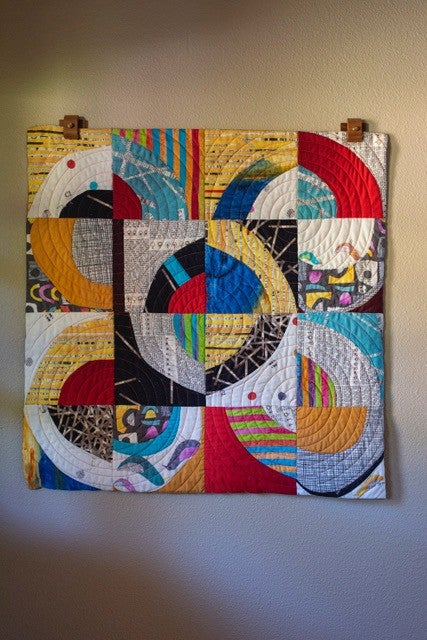 A patterned quilt hung up on a wall.