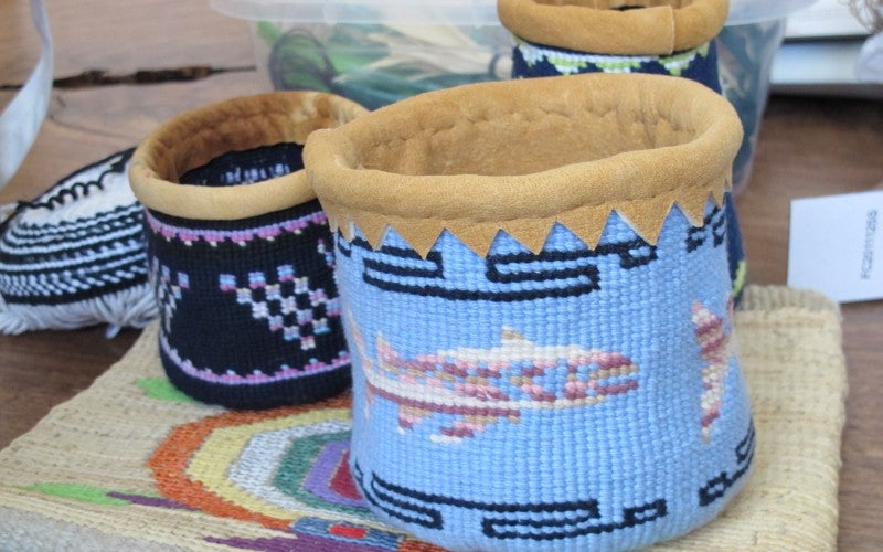 A large blue woven basket with fish patterning sits next to a small black and blue woven basket