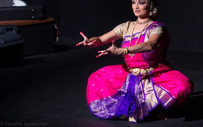 Sweta dancing, her arms reaching out to the audience 