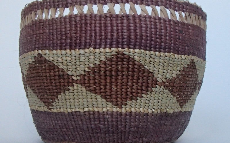 A brown and white woven, patterned basket on a white background.
