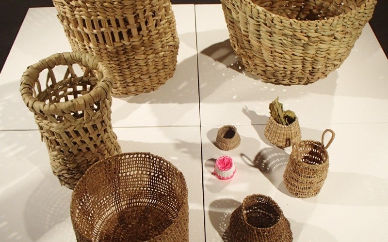 An assortment of tan woven baskets sitting on a white table with a black background.