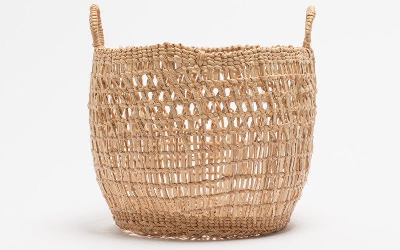 A tan woven basket with handles against a white background.