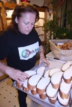 Linda Romero stands in La Perla Bakery in Klamath Falls, Oregon, and handles pieces of sliced bread. She wears a black t-shirt that says "La Perla Bakery".