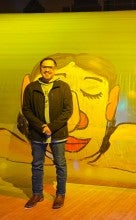 Eddie is standing in front of a wall painting.