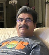 Dagoberto Morales Duran sitting on a couch wearing a grey t-shirt.