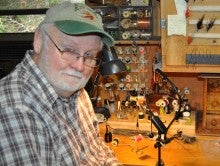 Joe Howell sitting at his workshop desk building fishing lures.