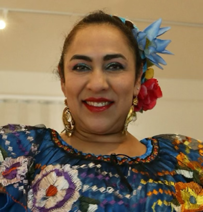 Kenya Márquez a smiles, wearing flowers in her hair.