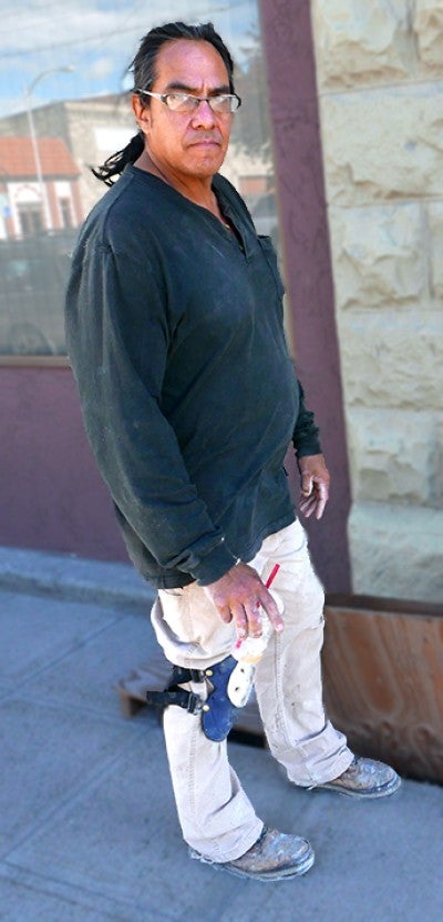 Dave Gagnon stands outside next to white masonry in Historic Baker City, Oregon. He wears a black long sleeved shirt.