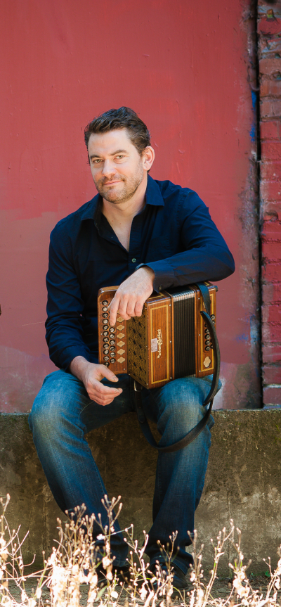 Johnny B. Connolly sits with an accordion on lap. 
