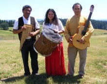 Members of Grupo Condor stand outside holding woodpipes, a drum, and an acoustic guitar.