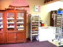 Indoor image of Panaderia Las Cuatas. There is a wooden cabinet and two metal racks full of pastries.