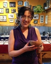 Awilda Medina Vazquez stands in Boriken restaurant in Beaverton, Oregon holding a handmade dita. She wears a dark purple tank top. 