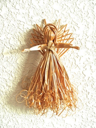 A wheat-woven angel against a white wall
