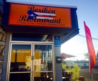 The entrance of Awilda's restaurant with a bright orange sign containing an image of the Puerto Rican flag and the name "Boriken Restaurant."
