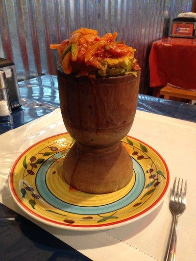 A traditional Puerto Rican dish served in a tall wood bowl placed on a colorful plate.