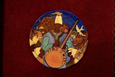 An art piece depicting a traditional Malian story, with a man sitting in the middle and surrounded by people and animals.