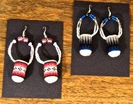Two pairs of earrings in the shape of miniature baskets. One pair is red, black, and white. The other pair is blue, black, and white.